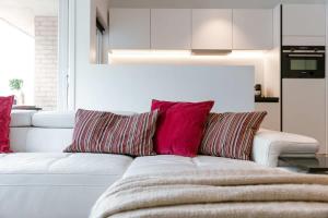 un sofá blanco con almohadas rojas en la sala de estar. en Centrally located apartment in Middelkerke, en Middelkerke