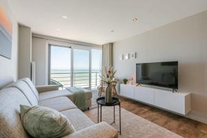 a living room with a couch and a television at Cosy apartment with frontal seaview in Nieuwpoort