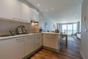 a kitchen with white cabinets and a dining room at Cosy apartment with frontal seaview in Nieuwpoort
