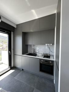 a kitchen with white cabinets and a stove and a window at Sunrise and Sunset Palio Sea View Appartment in Kavala