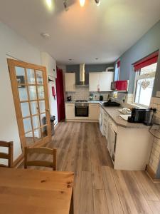 uma cozinha com armários brancos e piso em madeira em Downs Gate Cottage em Eastbourne