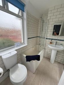 Baño blanco con aseo y lavamanos en Downs Gate Cottage, en Eastbourne