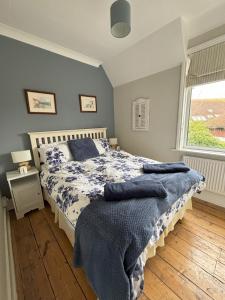 um quarto com uma cama com lençóis azuis e uma janela em Downs Gate Cottage em Eastbourne