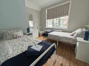 a bedroom with two beds and two windows at Downs Gate Cottage in Eastbourne