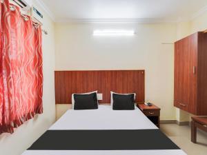 een slaapkamer met een wit bed en een houten hoofdeinde bij OYO Meenaachi Inn in Chennai