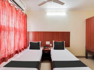two beds in a room with red curtains at OYO Meenaachi Inn in Chennai