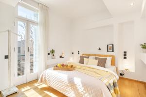 a white bedroom with a bed with a basket of fruit on it at OPEN SKIES- PENTHOUSE IN PLAKA- ACROPOLIS VIEW! in Athens