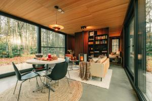 a living room with a table and chairs in a house at Cabin in the woods with hottub in Stekene