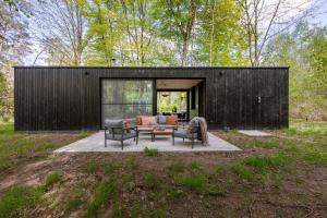 a black house with two chairs and a couch at Cabin in the woods with hottub in Stekene