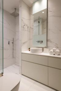 a white bathroom with a sink and a mirror at Urban APT with Stunning Acropolis View & Roofdeck in Athens