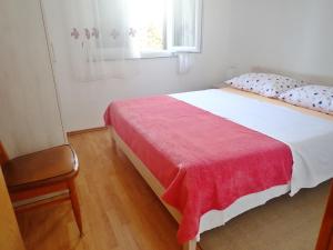 Un dormitorio con una cama con una manta roja y una ventana. en Apartmani Katica-u blizini plaže "Pisak", en Seline