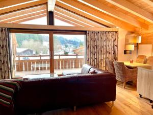 a living room with a couch and a large window at Alpenlodge Charivari - SommerBergBahn unlimited kostenlos in Oberstdorf