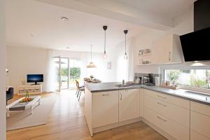 uma cozinha com armários brancos e uma sala de estar em Ferienhaus Moos em Wasserburg