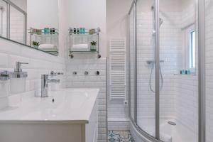 La salle de bains blanche est pourvue d'un lavabo et d'une douche. dans l'établissement Warm & cozy lateral seaview apartment, à Ostende
