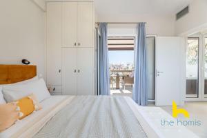 1 dormitorio con 1 cama y puerta a un balcón en Athenian Sky Retreat: Jacuzzi & Fresh Elegance! en Atenas