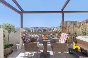 a patio with a table and chairs on a balcony at Athenian Sky Retreat: Jacuzzi & Fresh Elegance! in Athens