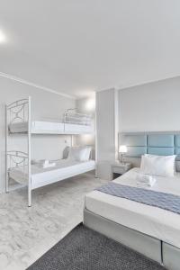 a white bedroom with two bunk beds and a rug at Chic, Modern Seaside Oasis in Sunny Piraeus! in Piraeus