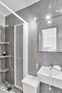 a bathroom with a sink and a shower with a mirror at Chic, Modern Seaside Oasis in Sunny Piraeus! in Piraeus