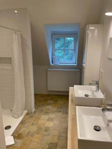 a bathroom with two sinks and a tub and a window at Two guest-rooms in stylish villa - free bikes in Bruges