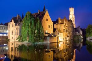 an old building with trees in the water at night at Two guest-rooms in stylish villa - free bikes in Bruges
