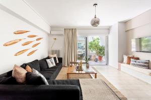 ein Wohnzimmer mit einem schwarzen Sofa und einem Tisch in der Unterkunft Fresh Detailed Stylish Apartment at Acropolis in Athen