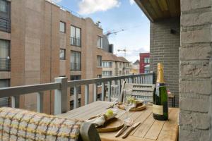 een fles wijn op een houten tafel op een balkon bij Stunning new and modern apartment with large terrace and free parking in Knokke-Heist