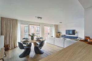 een woonkamer met een tafel en stoelen en een bank bij Stunning new and modern apartment with large terrace and free parking in Knokke-Heist