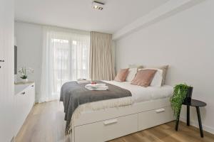 een witte slaapkamer met een bed en een raam bij Stunning new and modern apartment with large terrace and free parking in Knokke-Heist