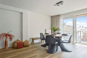 een eetkamer met een tafel en stoelen en een groot raam bij Stunning new and modern apartment with large terrace and free parking in Knokke-Heist