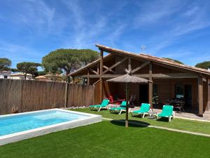 Casa con piscina, sillas y sombrilla en Villas Magnolia y Brezo, en Chiclana de la Frontera