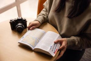 a woman is reading a book with a camera at Haka House Queenstown in Queenstown