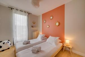 Duas camas num quarto com paredes cor de laranja em L'Echoppe Bordelaise - Très belle maison avec jardin em Bordéus