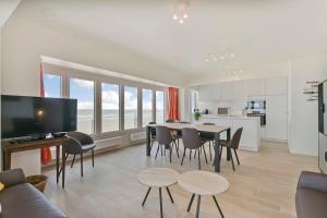 ein Wohnzimmer mit einem Tisch und Stühlen sowie eine Küche in der Unterkunft Majestic Apartment With Breathtaking Sea View in De Haan