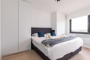 a white bedroom with a large bed with blue pillows at Huswell - Renovated apartment with sea view and parking in Knokke-Heist