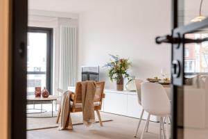 a kitchen with white furniture and a table and chairs at Huswell - Renovated apartment with sea view and parking in Knokke-Heist