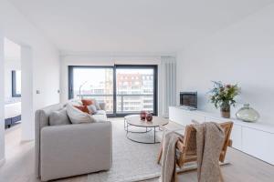 a living room with a couch and a table at Huswell - Renovated apartment with sea view and parking in Knokke-Heist +17 photos