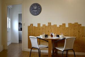stół z dwoma krzesłami i zegarem na ścianie w obiekcie Hôtel Alizéa w La Rochelle