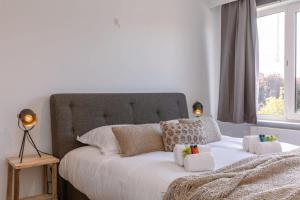 a bedroom with a white bed with pillows and a window at Huswell - Cosy apartment with vintage interior in De Haan