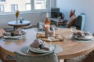 a wooden table with plates and wine glasses on it at Huswell - Cosy apartment with vintage interior in De Haan