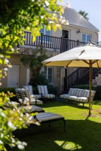 a patio with chairs and an umbrella in the yard at Lemoenkloof Boutique Hotel in Paarl