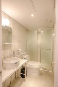 a white bathroom with a sink and a toilet at Upflo Hostel in Seoul