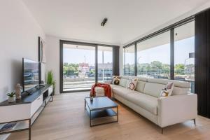 New, luxurious and modern apartment with private parking في كوكسيجدي: غرفة معيشة مع أريكة بيضاء ونوافذ