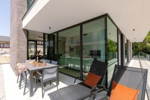 New, luxurious and modern apartment with private parking في كوكسيجدي: منزل زجاجي به طاولة وكراسي على الفناء