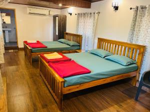 two twin beds in a room with wood floors at GOKARNA JUNCTION - A vintage homestay in Gokarna