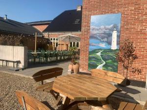 a picnic table and chairs and a painting of a lighthouse at Kroghuset - Det Lille Hotel in Tarm