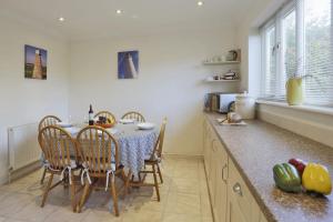 a kitchen with a table and chairs and a kitchen with a counter at Dovedale in Reydon