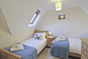 a attic bedroom with two beds and a window at Dovedale in Reydon