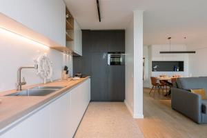 een keuken met een spoelbak en een woonkamer bij Huswell - Cosy apartment with terrace overlooking the sea in Middelkerke +14 foto's