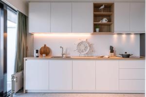 een keuken met witte kasten en een spoelbak bij Huswell - Cosy apartment with terrace overlooking the sea in Middelkerke