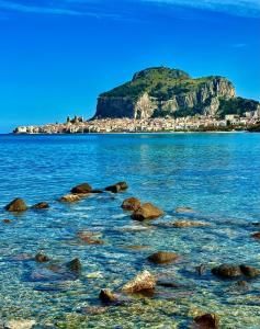 ein Gewässer mit Felsen vor einem Berg in der Unterkunft Family House in Cefalú